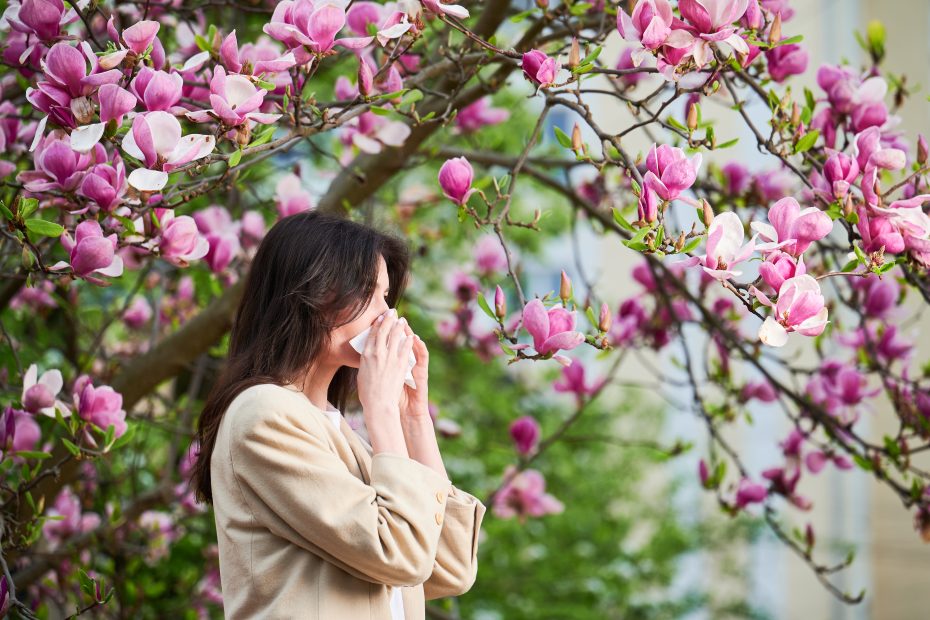Frau vor blühendem Strauß - Allergien im Frühling